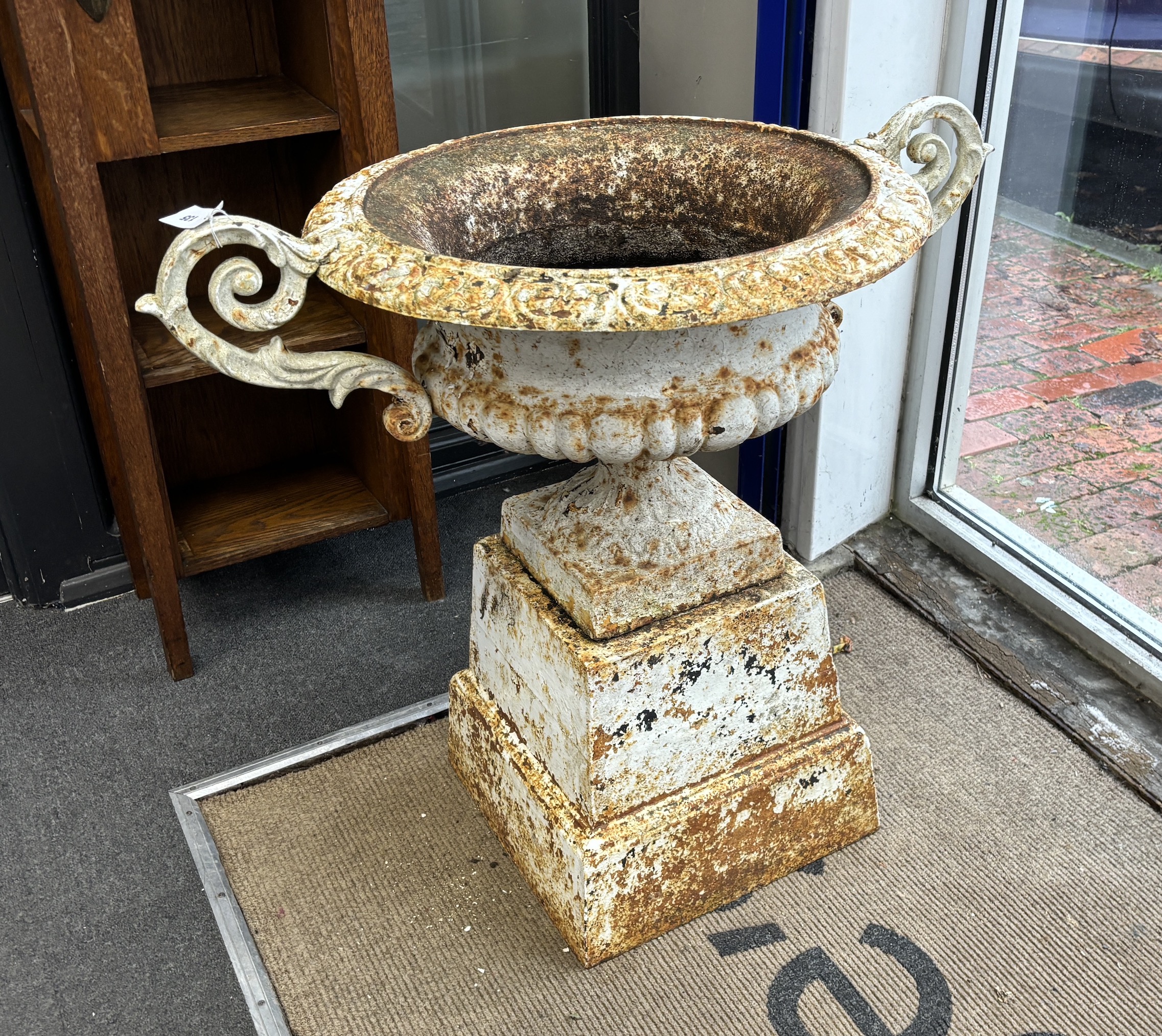 A pair of Victorian circular cast iron campana shaped garden urns, on square cast iron plinths, diameter 60cm, height 80cm